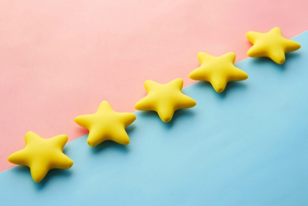 a row of five yellow stars sitting on top of a blue and pink surface indicating reviews