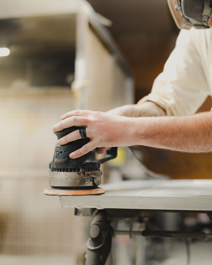 Person using an orbital sander to sand wood