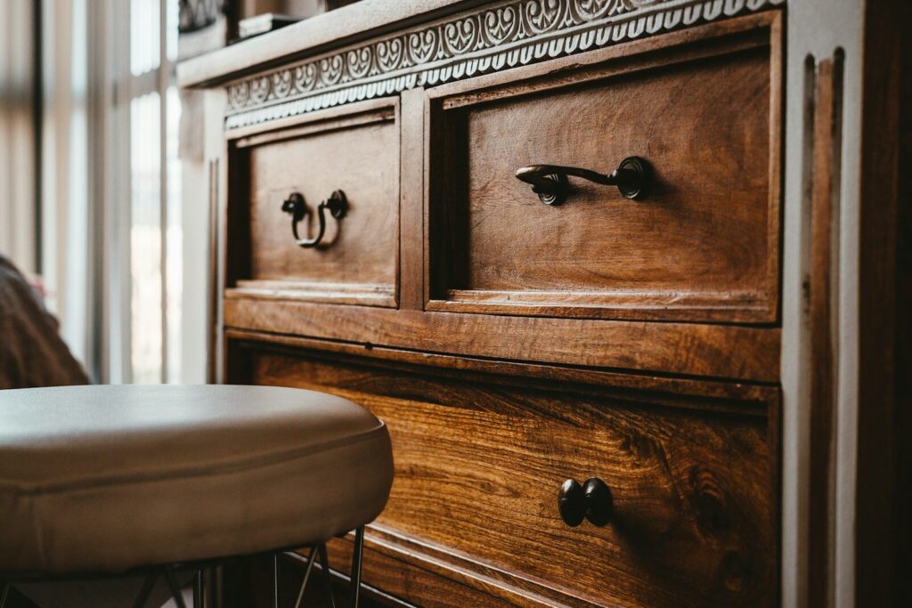 A close up of a carved brown oak wooden drawer chest that has been restored as part of a DIY furniture project