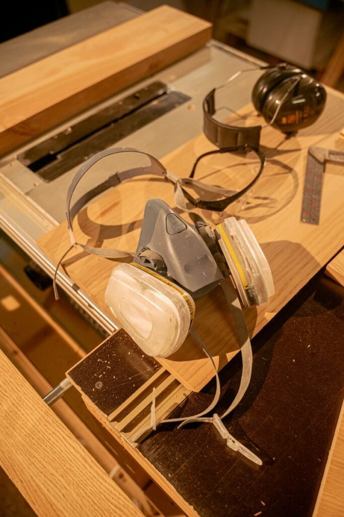 A close-up of safety gear including a respirator mask and ear protection in a workshop setting.