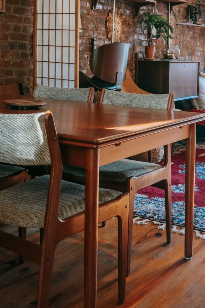 Classic wooden table and chairs placed on parquet floor with traditional carpet in vintage styled apartment