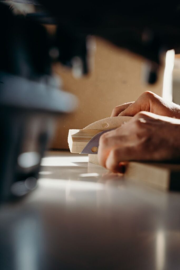 Close-up of a carpenter sanding wood indoors by hand using a sanding block, showcasing craftsmanship.
