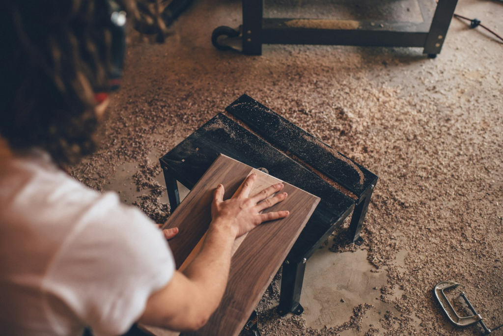 A woman sanding a piece of wood as part of a DIY furniture project