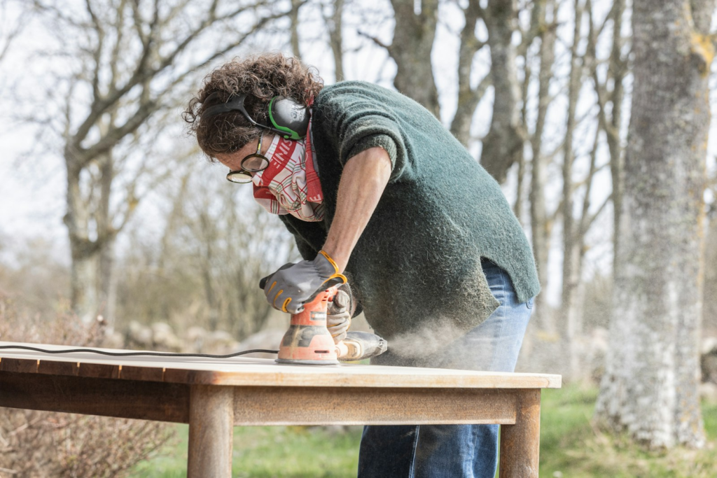 woman sanding a wooden table with an orbital sander