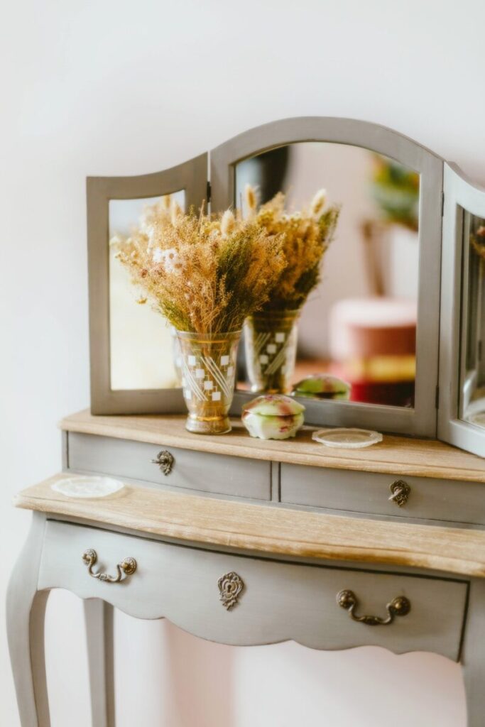 A restored painted dresser with a mirror and a vase of flowers on it