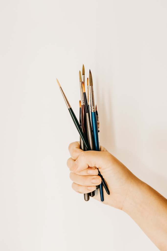Collection of small artist's paintbrushes being held in a woman's hand