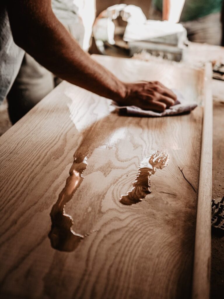 a person oiling a wooden table with a cloth