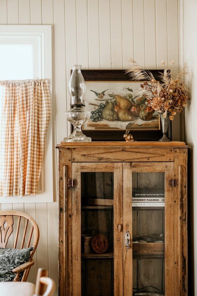a wooden cabinet with a vase and glass on top. Farmhouse style interior